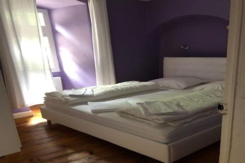 Ce lit se trouve dans un dortoir doté d'un mur violet. dans l'établissement Apartment in Serrières with Alps View Pool, cleaning included, à Serrières-en-Chautagne