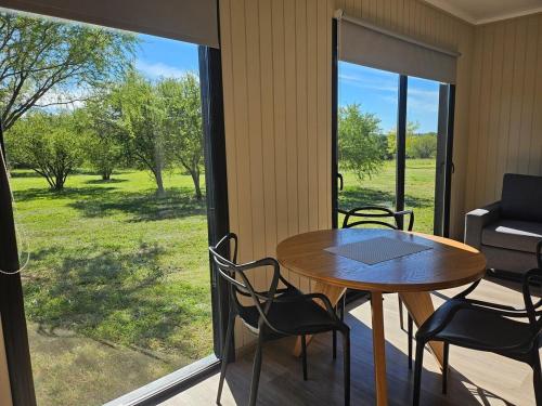 a table and chairs on a porch with a view of a yard at La Recompensa Tiny in Colonia Nuevo Paysandú
