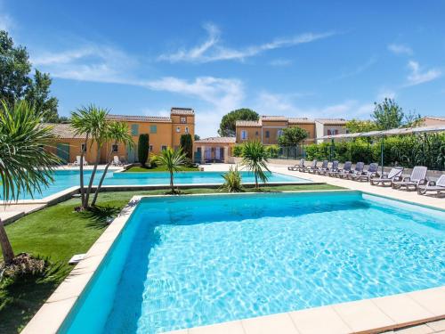 une piscine avec des chaises et des palmiers en face d'un bâtiment dans l'établissement Holiday Home in Arles with Pool & Terrace, cleaning included, à Arles