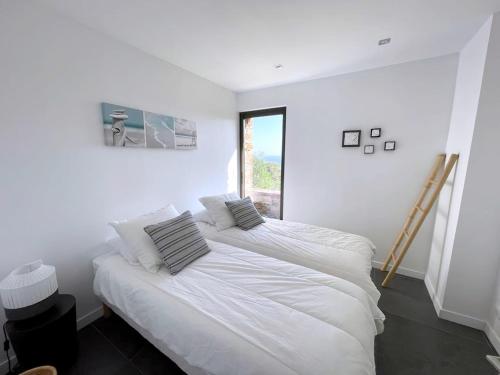 deux lits dans une chambre blanche avec une fenêtre dans l'établissement Villa in Gaou with Sea View and Beach, cleaning included, à Bormes-les-Mimosas