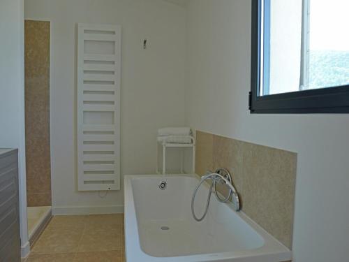 La salle de bains est pourvue d'une baignoire blanche et d'une fenêtre. dans l'établissement Villa in Malaucène with Private Pool, cleaning included, à Malaucène