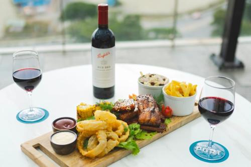 a table with a plate of food and two glasses of wine at Crowne Plaza Residences Port Moresby by IHG in Port Moresby
