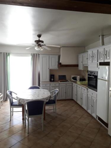 une cuisine avec des armoires blanches et une table et des chaises dans l'établissement Loc vacances appart T2 meublée 1 er proche plage, à Mèze