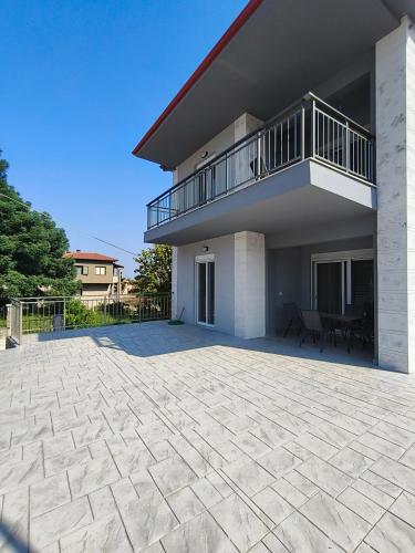 a large patio in front of a house with a balcony at Irina's Apartment 4 in Psakoudia