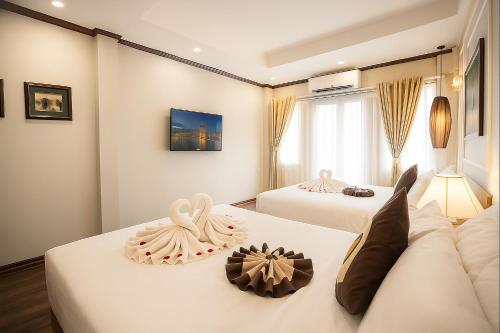 two beds in a hotel room with white sheets at Hanoi Sena Hotel & Travel in Hanoi