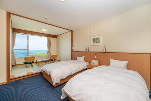 a hotel room with two beds and a large window at Kyukamura Echizen-Mikuni in Sakai