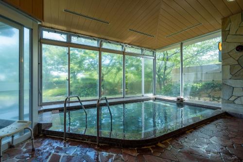 a large indoor pool in a house with windows at Kyukamura Echizen-Mikuni in Sakai