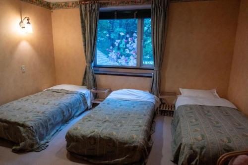 two beds in a room with a window at Pension Balmy in Nasu