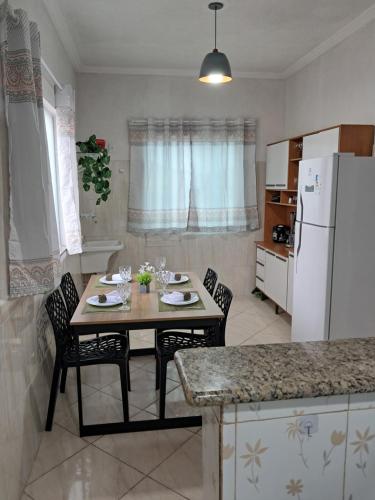 a kitchen with a table with chairs and a white refrigerator at Refúgio do Abricó - apto com ar e garagem in Rio das Ostras