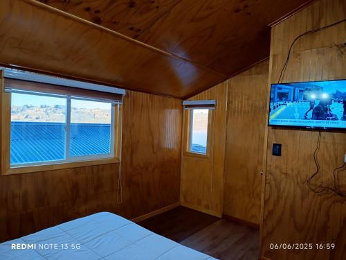a room with a tv and a bed and a window at CABAÑAS REY-MAR in Castro
