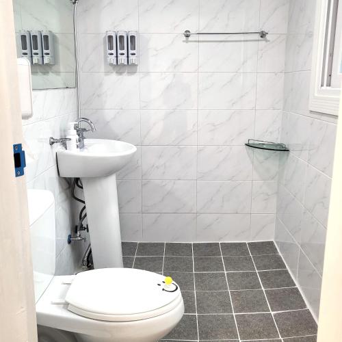 a white bathroom with a toilet and a sink at Humming stay in Seoul