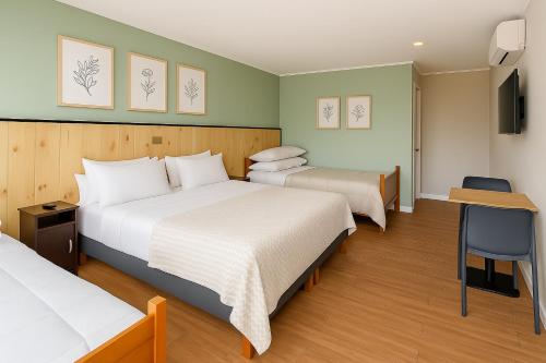una camera d'albergo con due letti e una televisione di Hostal Villarrica Express a Villarrica