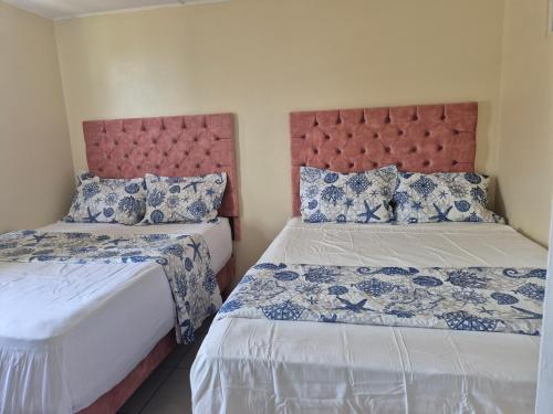a bedroom with two beds with blue and white sheets at Maranatha villa in Discovery Bay