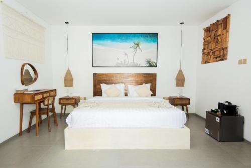a white bedroom with a bed and a desk at Baliterraneo Boutique Resort in Seminyak