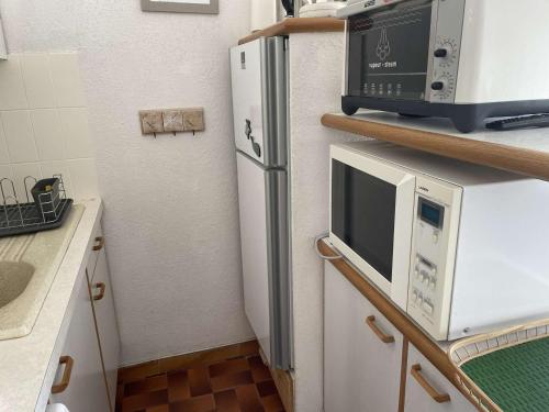 une cuisine avec un réfrigérateur et un micro-ondes dans l'établissement Studio + 2 cabines direct plage, terrasse, parking, 4 pers. - FR-1-731-142, au Grau-du-Roi