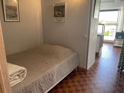 Ce petit lit se trouve dans un dortoir doté de carrelage. dans l'établissement Studio + 2 cabines direct plage, terrasse, parking, 4 pers. - FR-1-731-142, au Grau-du-Roi