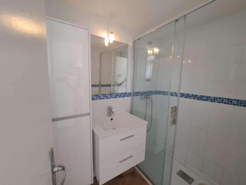 une salle de bain blanche avec un lavabo et une douche dans l'établissement Appartement 2 pièces en duplex, proche plage, parking privé - FR-1-326-861, à Marseillan