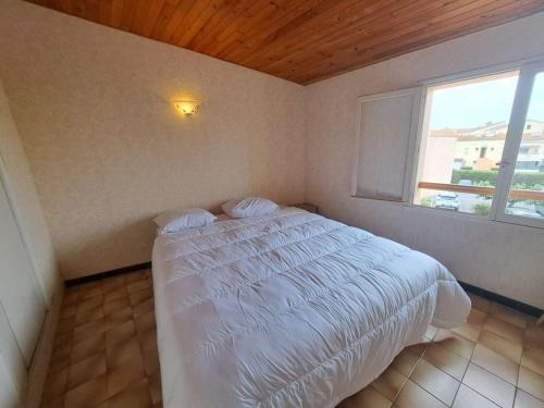 une chambre avec un lit blanc avec une fenêtre dans l'établissement Appartement 2 pièces en duplex, proche plage, parking privé - FR-1-326-861, à Marseillan