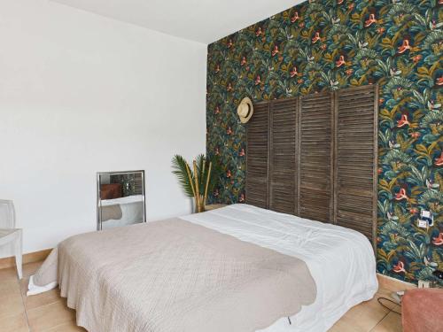 - une chambre avec un lit et un papier peint floral dans l'établissement Maison plain-pied 3 chambres, terrasse et climatisation, 8 pers - FR-1-326-860, à Marseillan