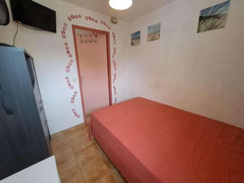 - une chambre avec un lit rouge et une porte dans l'établissement Appartement 2 pièces avec loggia aménagée à Marseillan-Plage - FR-1-326-863, à Marseillan
