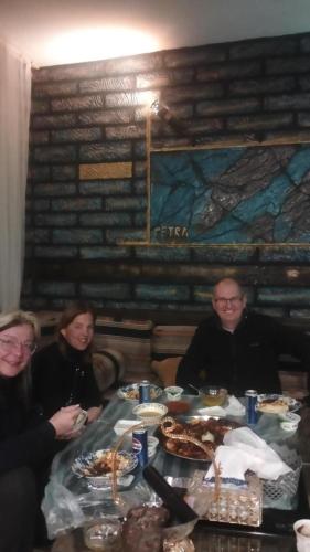 a group of people sitting at a table with food at Petra Musa Rural House in Wadi Musa