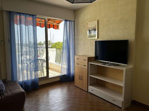 Il comprend un salon doté d'une télévision et d'un balcon. dans l'établissement Appartement Port Camargue - 4 Pers, Clim, Parking - FR-1-250-312, au Grau-du-Roi