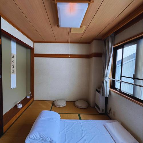 a small room with a bed and a window at SLEEEP JP Myoko in Myoko