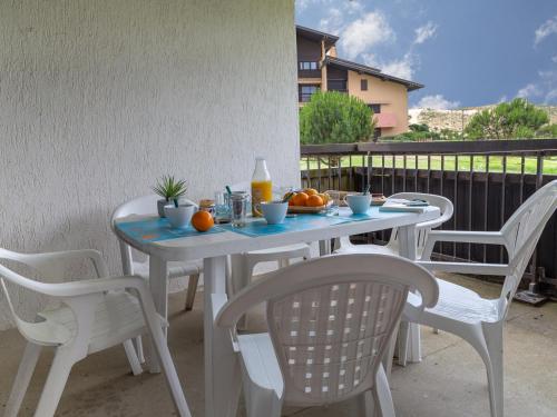 une table blanche et des chaises avec des oranges sur un balcon dans l'établissement Appartement Spacieux à Seignosse, Terrasse et Parking, à Proximité de la Plage - FR-1-239-401, à Seignosse
