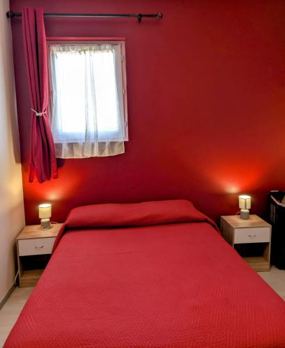 a red bedroom with a bed and a window at COMME A LA MAISON in Espéraza