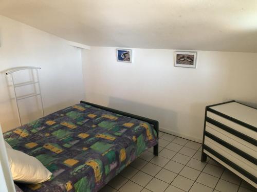 a small bedroom with a bed and two pictures on the wall at Appartement avec Terrasse et Piscine à Guéthary, Proche Plages - FR-1-239-604 in Guéthary