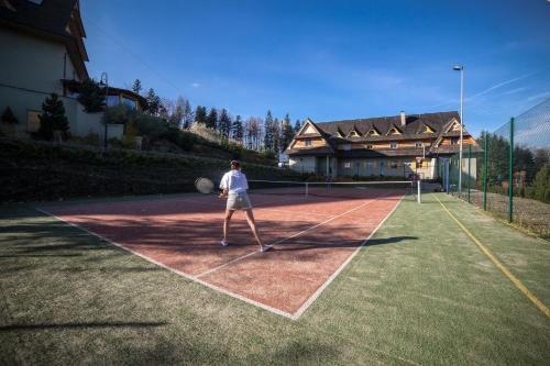 a man standing on a tennis court with a racket at Kocierz Resort in Targanice