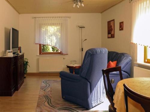 ein Wohnzimmer mit einem blauen Sessel und einem Fernseher in der Unterkunft Apartment view of fortress in Pirna in Pirna