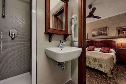 un bagno con lavandino e una camera con letto di Hotel Galleria a Venezia