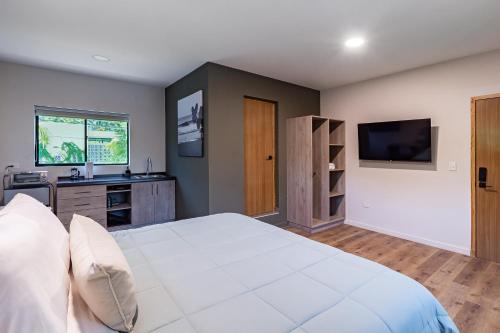 a bedroom with a large white bed and a television at Lora Loca Inn in El Zonte
