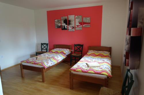 a room with two beds and a red wall at Penzion u Tomčalů in Terezín