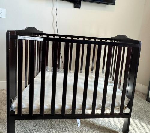 a black crib sitting in a room with a wall at Great Location Heart of Addison in N Dallas! in Addison