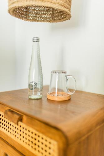 a glass bottle and two mugs on a wooden table at Baliterraneo Boutique Resort in Seminyak