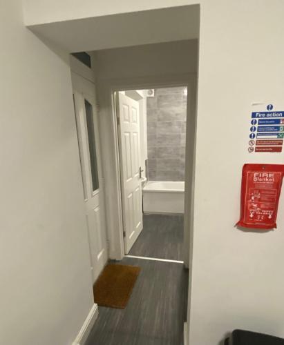 a hallway with a bathroom with a tub and a door at Warrington Guest House in Stoke on Trent