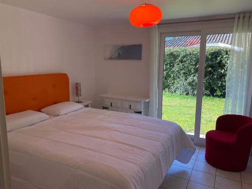 une chambre avec un lit, une chaise et une fenêtre dans l'établissement Maison de charme avec jardin, 9 couchages, Capbreton - FR-1-239-1035, à Capbreton