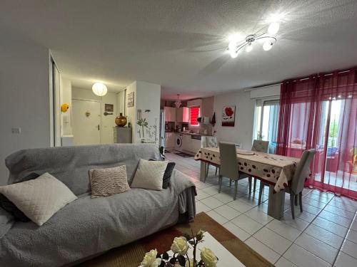 - un salon avec un canapé et une table à manger dans l'établissement Charmant appartement à Ondres pour 4 pers. avec loggia et parking - FR-1-239-1116, à Ondres