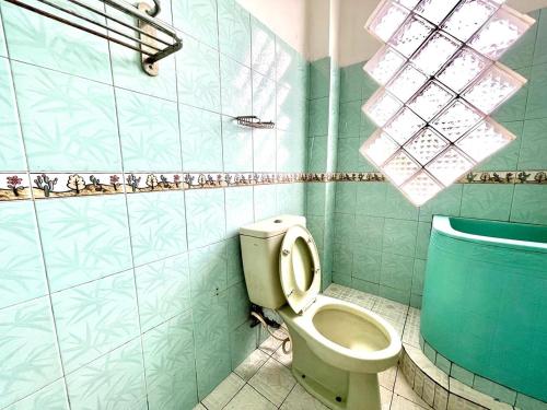a bathroom with a toilet and a blue tiled wall at Yani Guesthouse in Bukittinggi