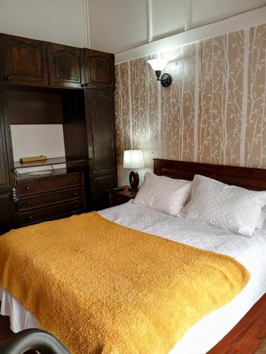 a bedroom with a bed with a yellow blanket on it at Casa 3 dormitorios in Santiago