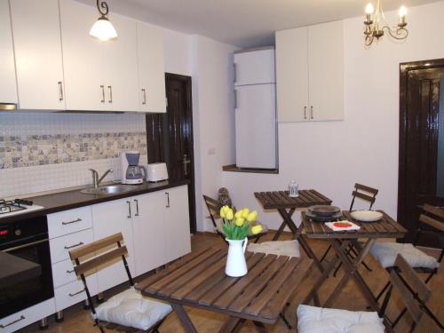 ブラショヴにあるBlue Houseの白いキャビネット、テーブルと椅子付きのキッチンが備わります。