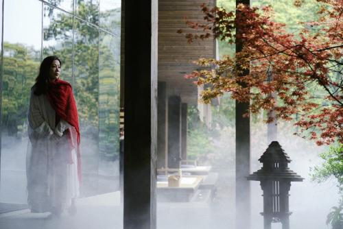 a woman standing in front of a window at 青城山坐忘森林疗愈酒店 in Dujiangyan