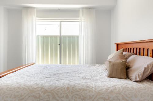 a bedroom with a white bed with a window at Large Premium Family Getaway with Centralised Heating in Shepparton