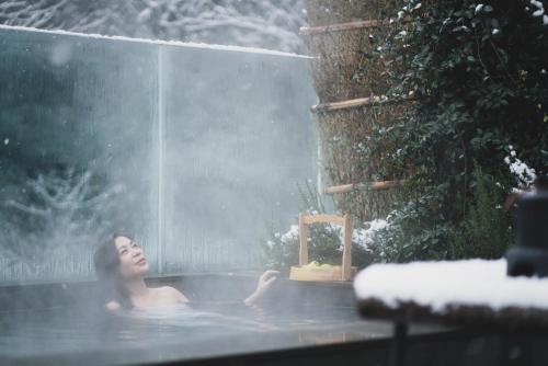 a woman sitting in a hot tub in the snow at 青城山坐忘森林疗愈酒店 in Dujiangyan