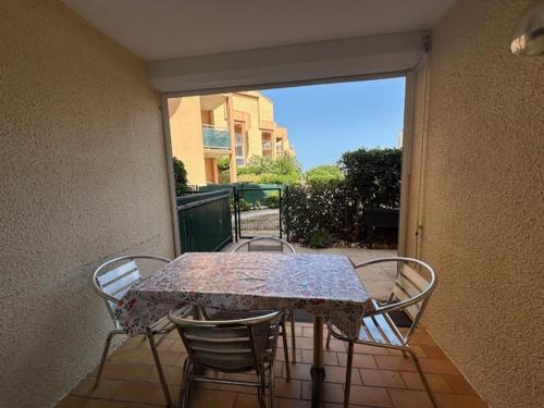 une table et des chaises sur une terrasse avec une fenêtre dans l'établissement Le Barcarès T2 en RDC, 4 Pers, Accès Direct Plage, Animaux OK - FR-1-799-55, au Barcarès