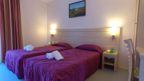 une chambre d'hôtel avec deux lits avec des draps violets dans l'établissement VVF Piriac-sur-Mer Bretagne Sud, à Piriac-sur-Mer