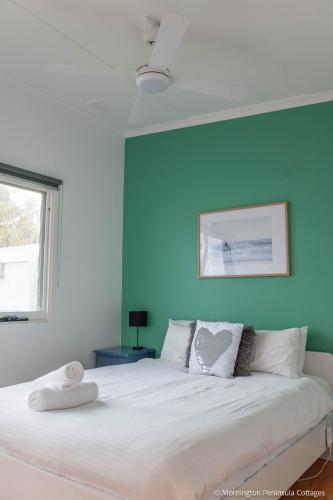 a bedroom with a large white bed with a blue wall at MP Beach Club in Tootgarook