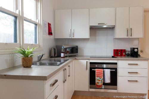a kitchen with white cabinets and a sink at MP Beach Club in Tootgarook